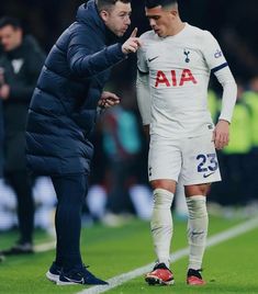 two soccer players are on the field with one pointing at another man's finger