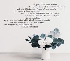 a vase filled with white flowers sitting on top of a table next to a wall