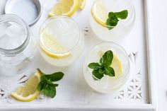 three glasses filled with lemonade and mint on a tray