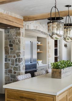 a kitchen with stone walls and an island in the middle, surrounded by wooden beams