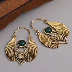 two pairs of gold earrings with green stone in the shape of an egyptian head and wings