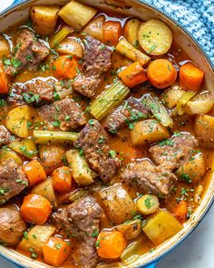 beef stew with carrots, potatoes and celery in a blue bowl