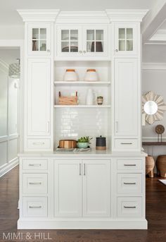 a kitchen with white cabinets and wooden floors