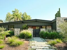 a house with stone steps leading up to the front door and entry way, surrounded by greenery