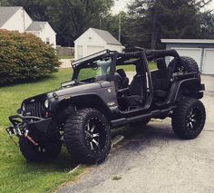 the jeep is parked on the side of the road in front of some houses and trees