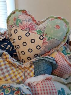 a heart shaped pillow sitting on top of a pile of fabric