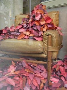 a chair covered in pink and orange leaves sitting on top of a glass floor next to a window