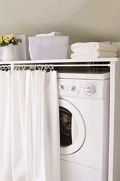 a washer and dryer sitting in front of a white shelf with towels on it