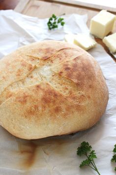 a loaf of bread sitting on top of a table next to butter and parsley