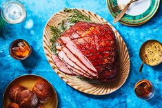 a large piece of meat sitting on top of a wooden plate next to other dishes