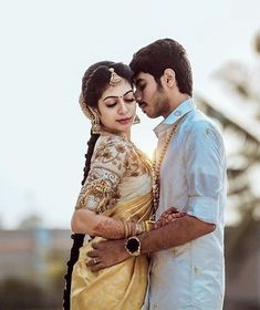 a man and woman standing next to each other with their arms around each other in front of the camera