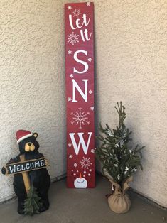 a wooden sign that says let it snow next to a potted plant and teddy bear