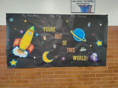 a bulletin board that says you're out of this world with space and rockets