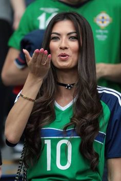 a woman with her hand up in the air while wearing a green shirt and black choker