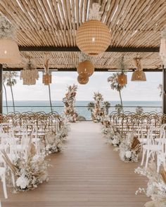 an outdoor wedding setup with white chairs and floral arrangements on the aisle, overlooking the ocean