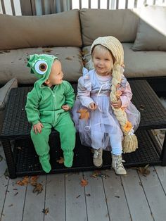 two children dressed up as monsters sitting on top of a couch next to each other