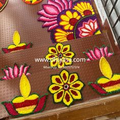 colorful flowers and candles are on the floor in front of a metal grating fence