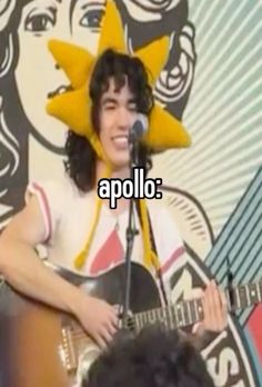 a man that is playing a guitar in front of a wall with the words apolo