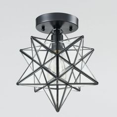 a ceiling light that has a star design on the front and bottom, with a small bulb