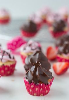 cupcakes with chocolate frosting and strawberries on the top are ready to be eaten