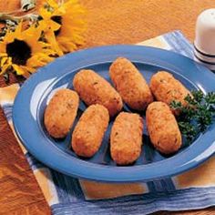 some food is sitting on a blue plate next to a cup and saucer with sunflowers in the background