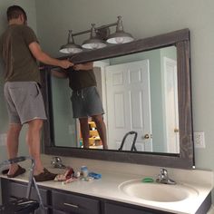 a man standing in front of a bathroom mirror holding onto the edge of a ladder