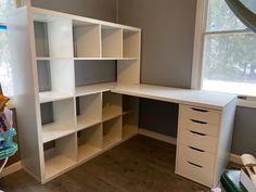 a corner desk with drawers and shelves in a room that is painted gray and white