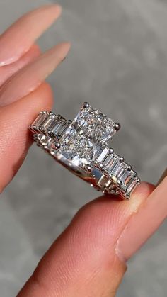 a woman's hand holding an engagement ring with three baguetts on it