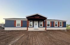 a blue and white house sitting on top of a dirt field