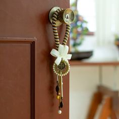 Antiqued medals of zamac metal invite you to live your faith freely. This artisanal-made door knob hanger by Mexico's Mony Lemus combines polyester and cotton threads and charming glass beads in a classic design full of devotion. A palette of brown, honey and ivory hues decorates each braid, while a ribbon crowns the piece. Door Knob Blessing Beads, Door Knob Hangers Wooden, Wooden Door Knob Hangers, Macrame Door Ornament Boy, Door Chain Lock Charms, Ribbon Crown, Doorknob Hangers, Spiritual Decor, Mens Jewelry Necklace