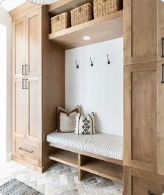 a wooden bench sitting in the middle of a room next to a wall with baskets on it