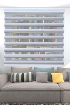 a gray couch sitting in front of a window covered in blinds