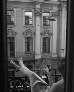 a woman laying on her back in front of a window looking out at the street