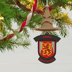 an ornament hanging from a christmas tree with a red and yellow crest on it