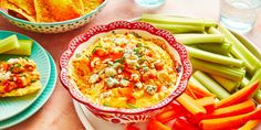 bowls of dip, celery sticks and carrots on a table