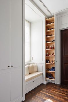 an empty closet with shoes on the shelves and a bench next to it in front of a window