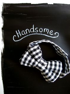 a black and white bow tie with the words handsome written on it in cursive writing