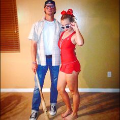 a man standing next to a woman in a red bathing suit and holding a baseball bat