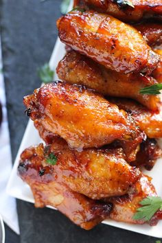 some chicken wings are piled on top of each other with garnish and parsley