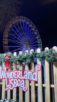 a wooden fence with a sign that says wonderland is boa in front of a ferris wheel