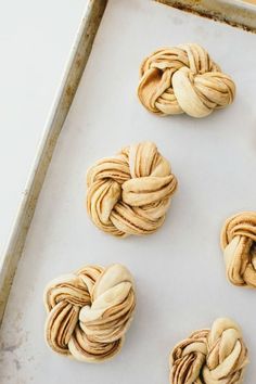 four knotted doughnuts sitting on top of a baking sheet