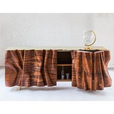 a sideboard with curtains on it in front of a brick wall