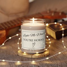 a lit candle sitting on top of a wooden table next to a string of lights