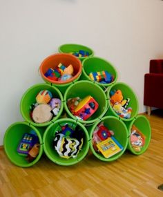 a stack of green plastic cups with toys in them on the floor next to a wall