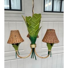 a chandelier with three lamps hanging from it's sides and a plant in the middle