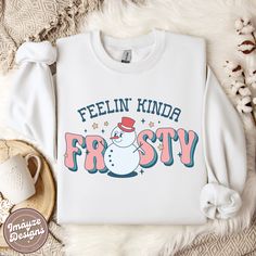 Feelin' Kinda Frosty Christmas Sweatshirt Funky Sassy Groovy Jumper Snowman Winter Cosy Sweater Ladies Christmas Gift for Her Womens Cute Welcome to ImayzeDesigns! ✨ Sleigh your seasonal style game with our sassy 'Feelin' Kinda Frosty' Christmas sweatshirt! This funky snowman design is sure to bring the perfect blend of cool and festive to your winter wardrobe ❄️💖☃️ THE SWEATSHIRT This classic Gildan 18000 unisex heavy blend crewneck sweatshirt is pure comfort! These garments are made from poly Winter Funny Print Crew Neck Top, Winter Crew Neck Top With Funny Print, Funny Print Long Sleeve T-shirt For Winter, Funny Print Long Sleeve Winter Tops, Winter Long Sleeve Tops With Funny Print, Cute Winter T-shirt With Graphic Print, Trendy Funny Print Tops For Winter, White Funny Print Winter Sweatshirt, White Winter Sweatshirt With Funny Print