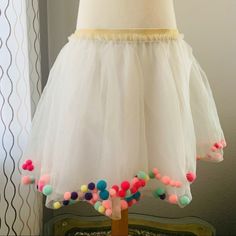 a white dress with colorful pom poms on it