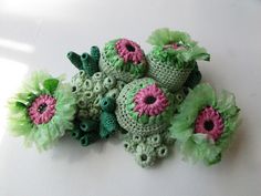 crocheted green and pink flowers sitting next to each other on a white surface