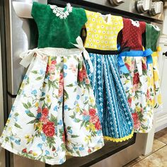 four dresses are hanging on a rack in the kitchen