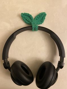 a pair of headphones sitting on top of a white table next to a green leaf